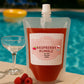 Plastic pouch of 'Raspberry Rumble' cocktail by Fiusion Cocktails with raspberries and a glass by a pool.