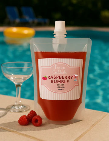 Plastic pouch of 'Raspberry Rumble' cocktail by Fiusion Cocktails with raspberries and a glass by a pool.